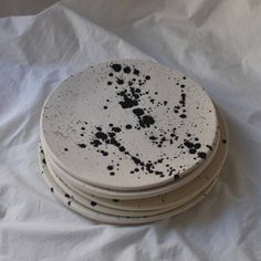 four white plates with black splatters on them