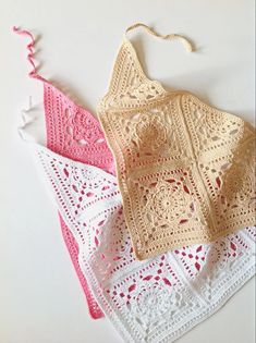 two crocheted aprons sitting next to each other on top of a table