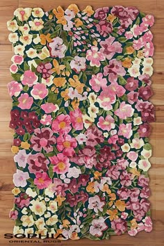 a rug with flowers on it sitting on top of a wooden floor in front of a wall