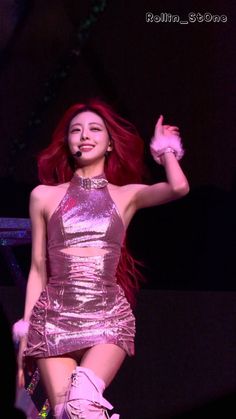 a woman with red hair wearing a pink dress and high heeled boots on stage