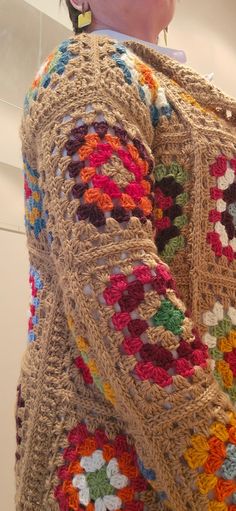 a woman is wearing a crocheted sweater and earrings