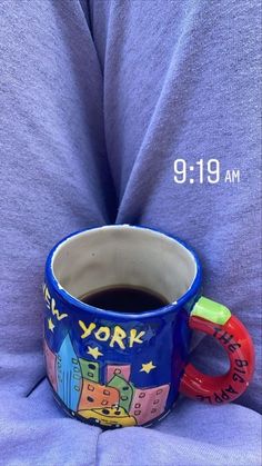 a blue mug with the words new york on it sitting in someone's lap