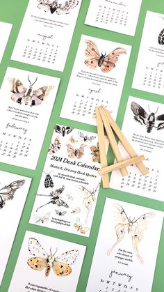 butterflies and moths calendars are displayed on a green table with wooden clothes pegs