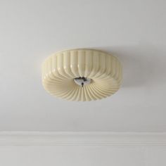 a white ceiling light mounted on the side of a wall in a room with no one around it