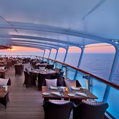 a dining area on the deck of a cruise ship at sunset with tables and chairs