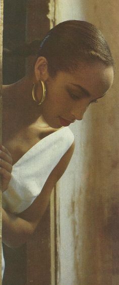 a young woman is holding onto a towel and looking down at the ground while wearing gold hoop earrings