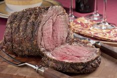 a large piece of meat sitting on top of a cutting board next to wine glasses