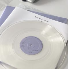 a white record sitting on top of a table next to a cell phone and envelope