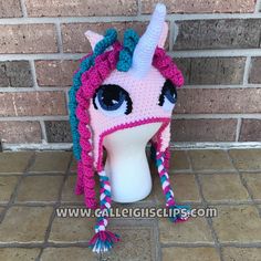 a crocheted pink unicorn hat with blue eyes