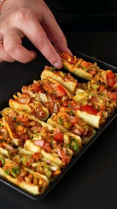 a person reaching for food in a pan on top of a black table with one hand