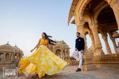 a man and woman are dancing in front of an ornate building with arches, pillars and archways