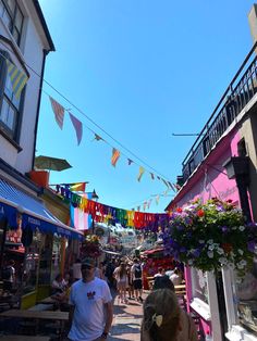 people are walking down the street in front of colorful buildings and bunting strung with flags