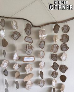 a group of handprints hanging on a wall next to a tree branch and sign