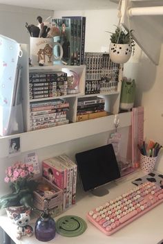 a desk with a computer, keyboard and many other items on it's shelves