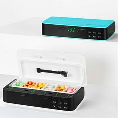 an electronic clock is sitting on top of a small box with food in it's lid