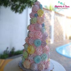 a cake made to look like a tree with flowers on the top is sitting in front of a swimming pool