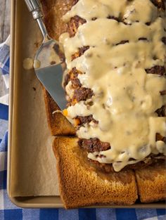 a loaf of bread covered in gravy on top of a blue and white checkered table cloth