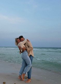 two people hugging each other on the beach