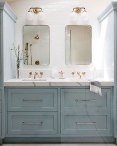 two sinks and mirrors in a bathroom with blue cabinets