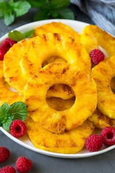 pineapple rings on a plate with raspberries and mint leaves next to them