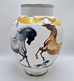 a white vase with horses painted on it