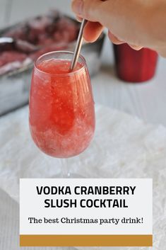 a person holding a spoon in a glass filled with vodka cranberry slush cocktail