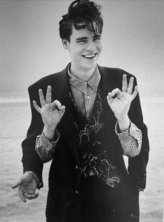 a man in a suit and tie making the peace sign with his hands while smiling