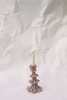 a small candle is sitting on a white surface with a sheet of paper behind it