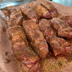 several pieces of meat sitting on top of a piece of paper with seasoning sprinkles