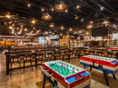 a large room with tables and foo - pong tables in the middle of it