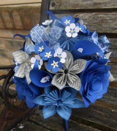 a bridal bouquet made out of blue and white paper flowers sitting on a bench