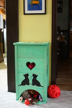 a green cabinet with dogs and hearts painted on the side, next to a red ball