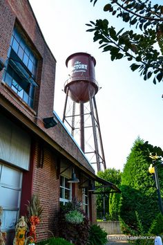 a brick building with a water tower in the back ground and plants growing on the side