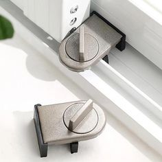 two metal latches on the side of a white window sill next to a potted plant