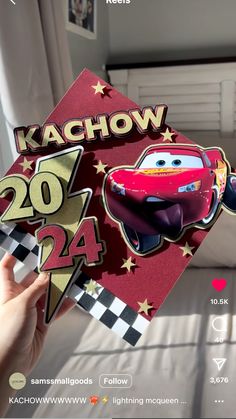 someone holding up a card with the character from cars on it in front of a bed