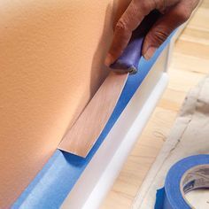 a person is using a blue tape to attach the edge of a piece of furniture