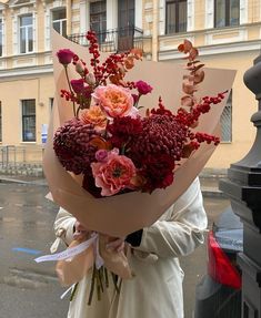 a woman holding a bouquet of flowers on the street