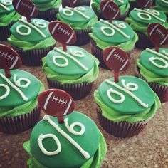 cupcakes decorated with green frosting and football decorations are displayed on a table