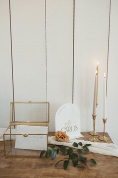 a table topped with candles and cards next to a white box filled with gold foil