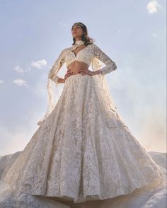 a woman in a wedding dress standing on top of a mountain with her hands on her hips