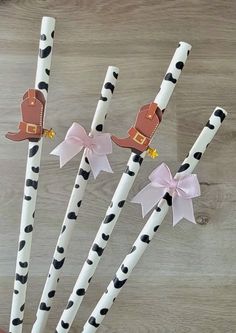 four paper straws decorated with black and white polka dots, pink bows and a cowboy hat