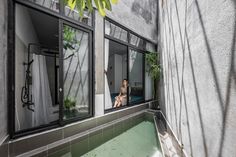 a woman is sitting in the window looking out at the street outside her apartment building