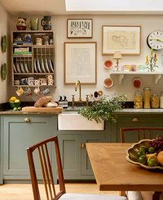 a kitchen filled with lots of green cabinets next to a wooden dining room table and chairs