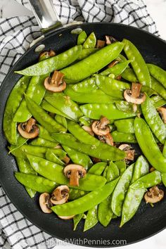 green beans and mushrooms are cooking in a skillet on a table with a checkered cloth