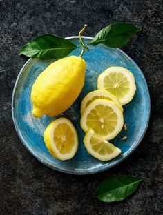 a blue plate topped with sliced lemons and leaves