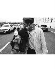 a man and woman walking down the street with cars in the backgrouds