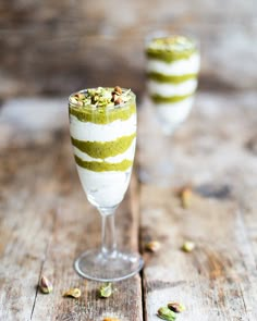 two glasses filled with dessert sitting on top of a wooden table