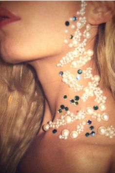 a close up of a woman's neck with pearls and jewels on her chest