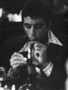 a man sitting at a table eating food and drinking from a glass in front of him