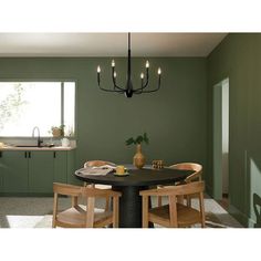 a dining room with green walls and wooden chairs